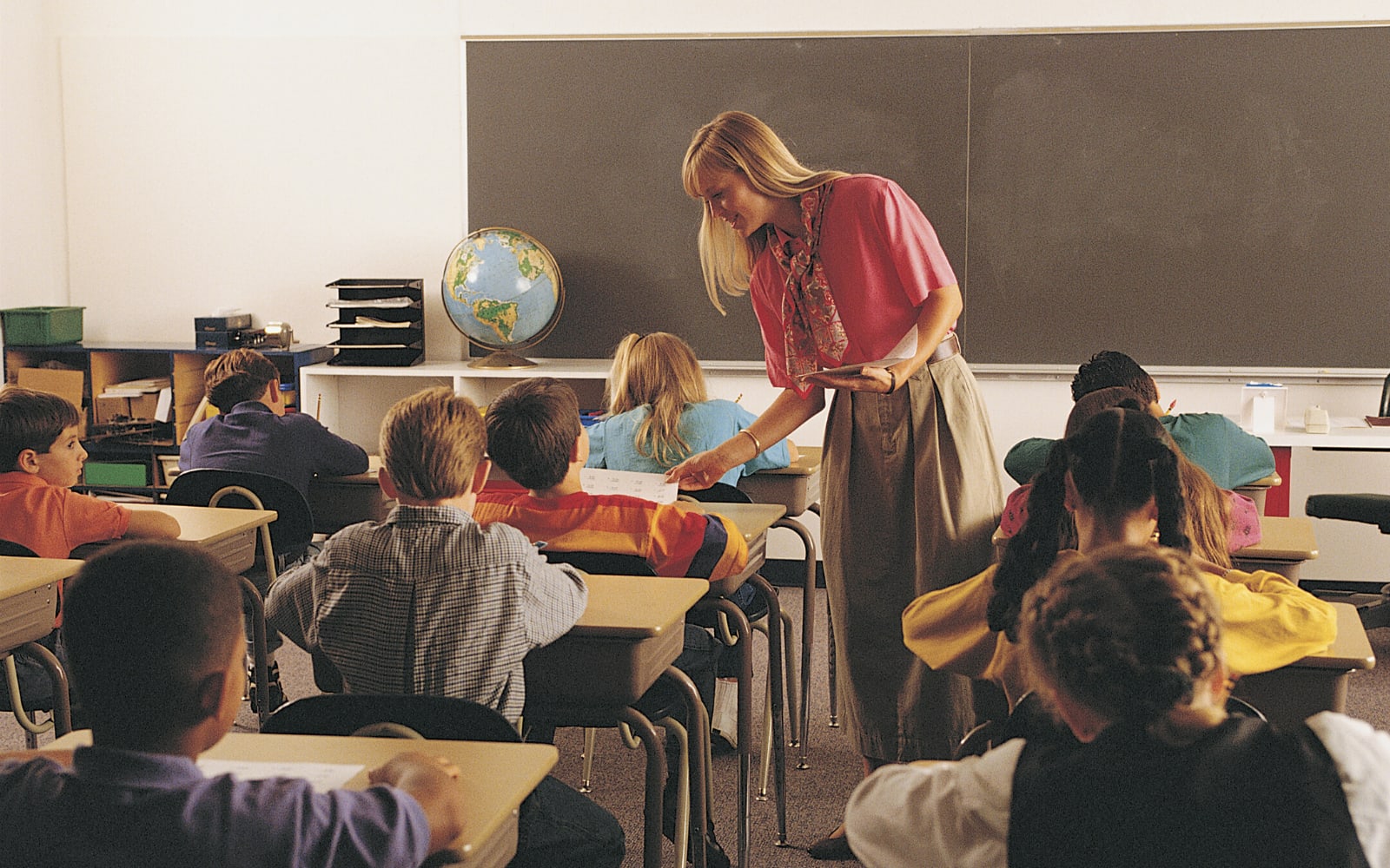 Teacher in an old classroom with pupils shown.
